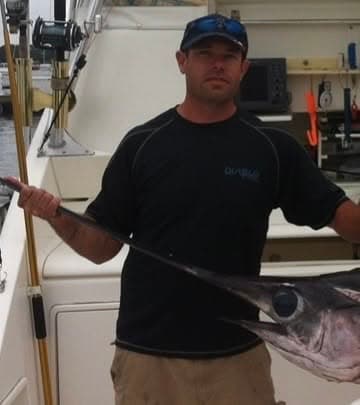 Quepos Charter Fishing captain holding a marlin aboard the boat